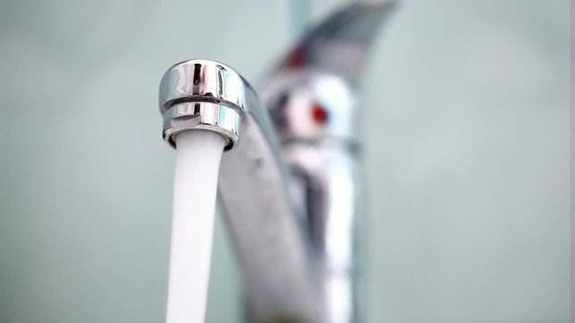 Man's hand starting and stopping tap water in bathroom
