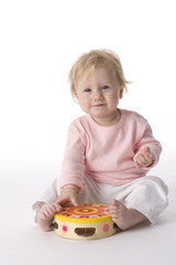 Baby girl sits on the floor with a toy drum