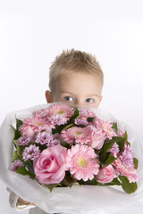 Little boy is hiding behind a bouquet of pink flowers