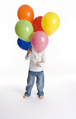 Little boy is hiding behind a bunch of balloons