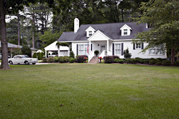 1950's  cottage with flag and vintage car in driveway