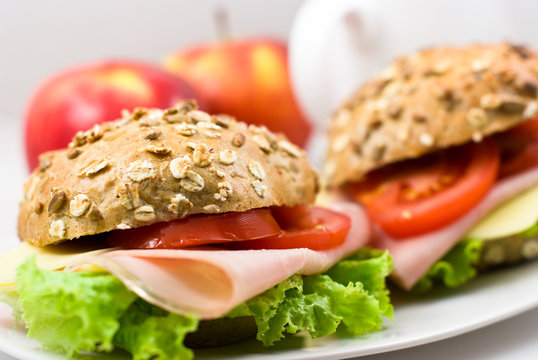 Close up of two sandwiches with ham and vegetables