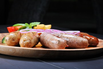 Assortment of grilled sausages on the wooden plate
