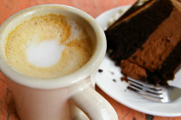 frothy coffee and piece of double chocolate cake
