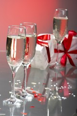 Glasses of champagne, gifts with red tapes and bows