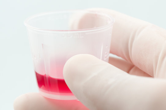 Cough syrup in cup held by medical professional