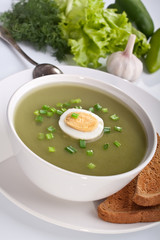 serving of spinach cream soup with vegetables at the back