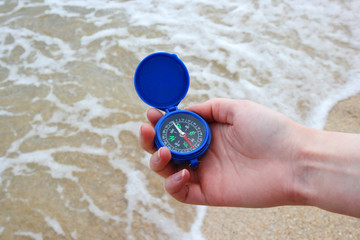 Dark blue compass in hands on a background a sea
