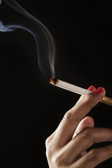 female fingers holding burning cigarette