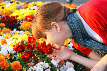 Cute girl with scarf sniffing flowers at the sunset