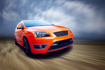 Foto op Plexiglas Beautiful orange sport car on road © Andrii IURLOV