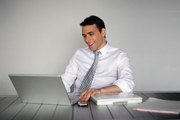 homme d'affaires souriant assis devant un ordinateur portable