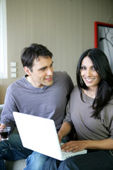 Homme et femme souriants assis devant un ordinateur portable