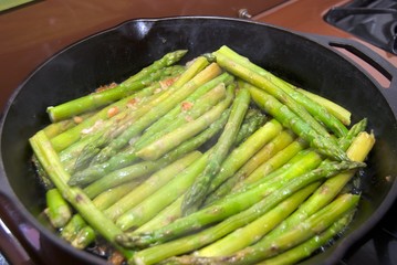 Asparagus sautéing in a skillet.