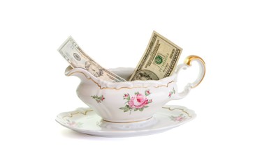 Vintage porcelain sauce-boat with dollar bills isolated