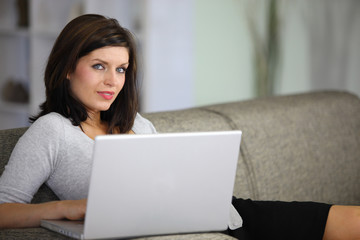 femme assise sur un canapé devant un ordinateur portable