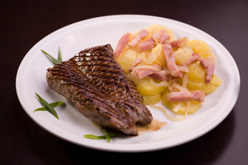 Steak with potatoes isolated on dark background
