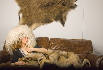 young girl in fur skins has a rest on a sofa