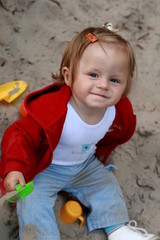 Fototapeta premium little girl plays in the sand box