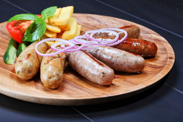 Assortment of grilled sausages on the wooden plate