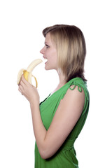 girl in a green dress eats a banana