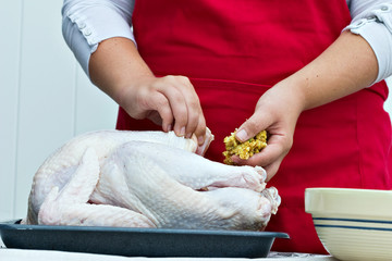 Woman's hands stuffing a large turkey for a holiday dinner.
