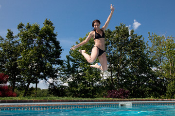 Woman in black bikini jumping into pool