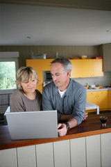 homme et femme devant un ordinateur portable dans une cuisine