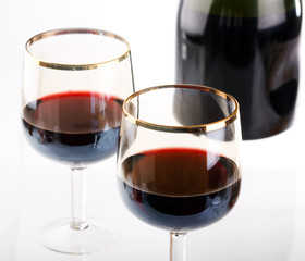 Glass of red wine with glass and bottle