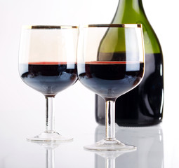 Glass of red wine with glass and bottle