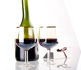 Glass of red wine with glass and bottle