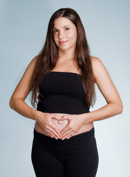 Attractive pregnant woman making heart shape