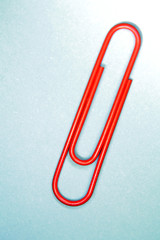 One red paper clip on blue
