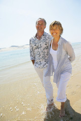 homme et femme souriants se promenant au bord de la plage