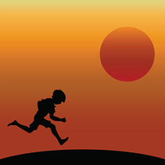 Young boy running silhouetted against a dawn or dusk sky
