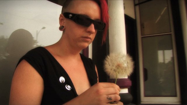 (1107) Tattooed young woman with Mohawk making dandelion wish