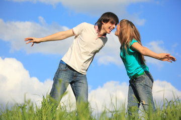 laughing young pair looks against each other in grass against  s