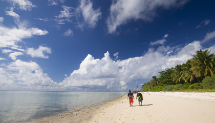 2 men walking on tropical beach