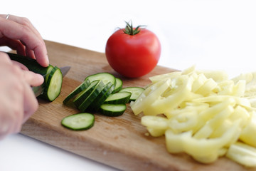 Hand cut gherkin, paprika and tomato on wooden plate