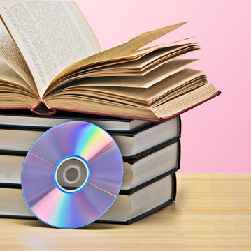 Pile of books  and DVD disk as symbols of old and new methods of