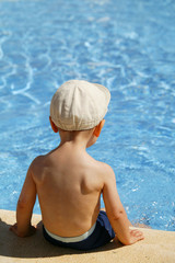 petit garçon assis près d'une piscine