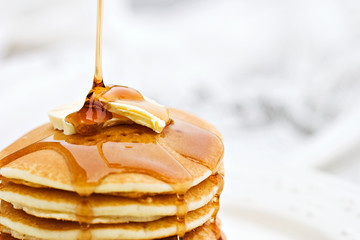 Maple syrup pouring onto pancakes. - Powered by Adobe