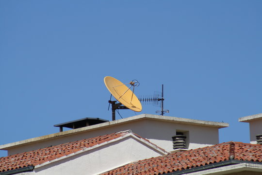 Antena parabolica amarilla en el tejado.
