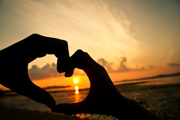 Heart fingers love concept at sunset