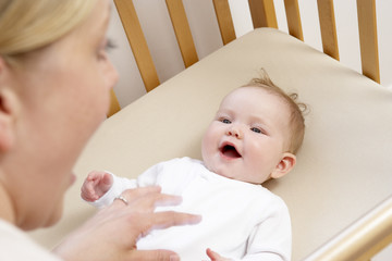 Mother Playing With Baby In Cot