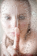 showering woman shot from behind glass