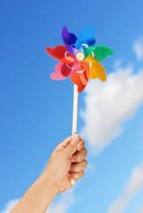 Hand holding pin wheel against sky