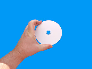 Hand holding blank CD or DVD media with blue background
