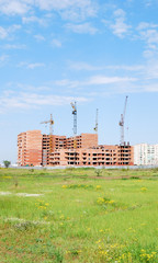 residential building under construction and four cranes against