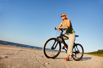 Fototapeta na wymiar Young woman with bicycle in beach